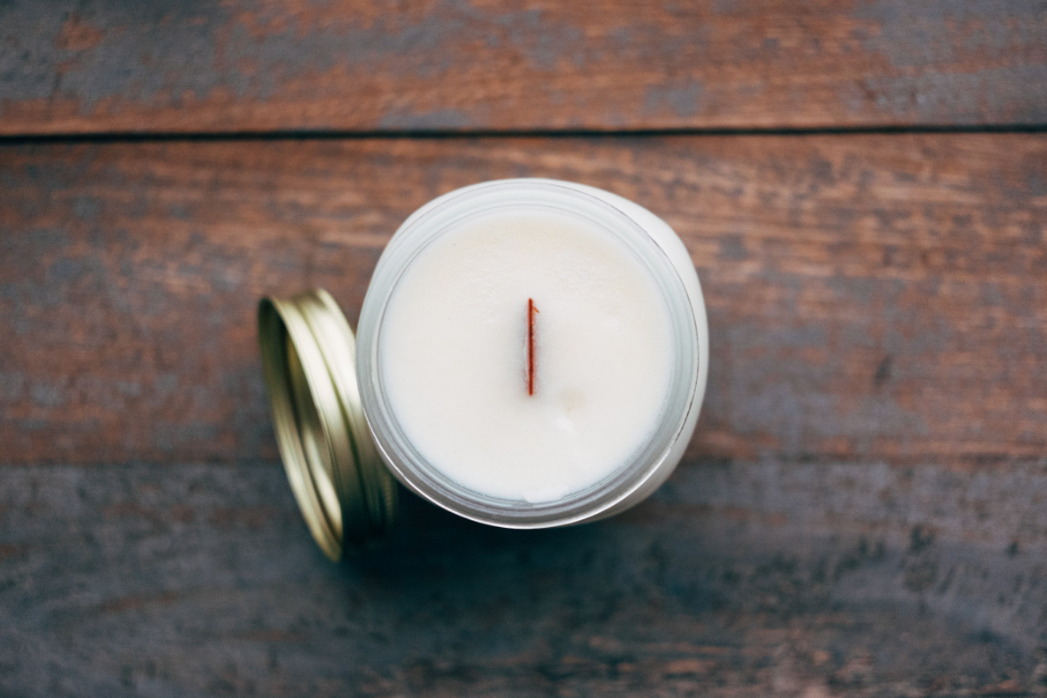 A white candle in a glass jar on a wooden vanity - the capsule vanity philosophy