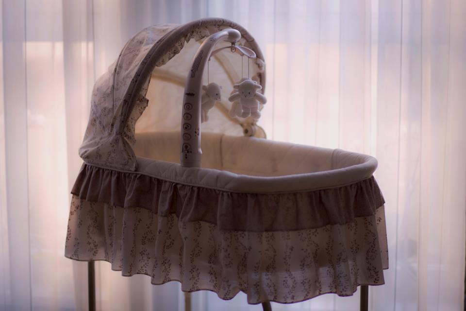 A bassinet with a mobile in soft window light - building a non-toxic nursery